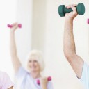 A group of smiling seniors lifting small dumbells in an exercise class
