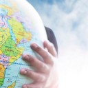 Globe being held outdoors with blue sky and clouds in the background