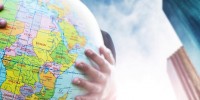 Globe being held outdoors with blue sky and clouds in the background