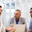 Doctor in a meeting with three others, laptop open alongside him