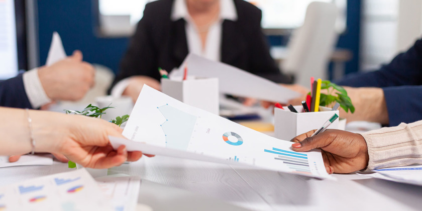 A piece of paper showing charts is passed from one hand to another