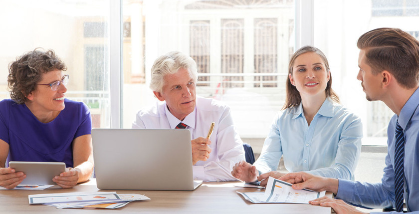 Four people of mixed ages having a discussion in a business setting